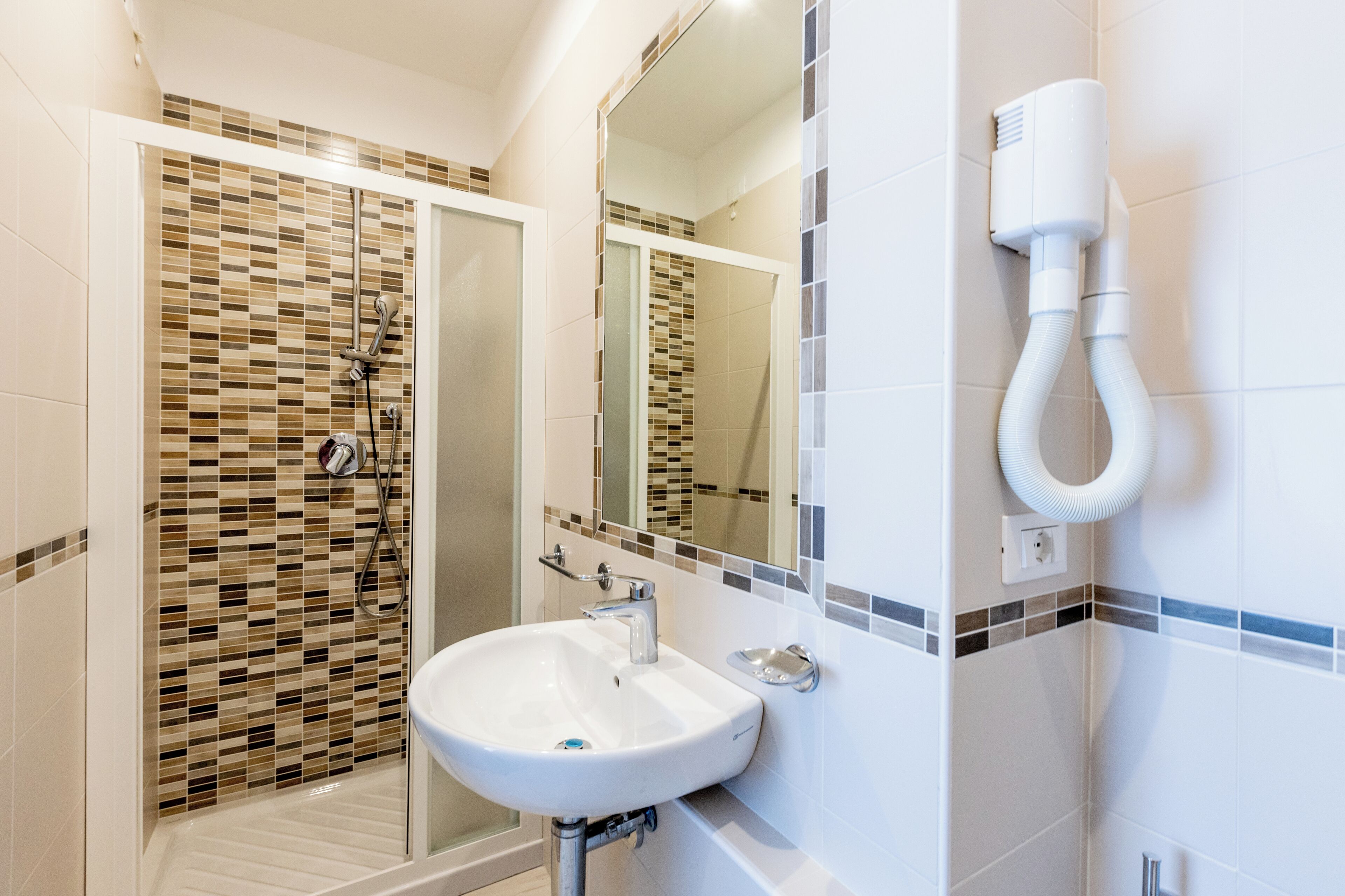 Un bagno con cabina doccia in vetro, un lavandino bianco e uno specchio.