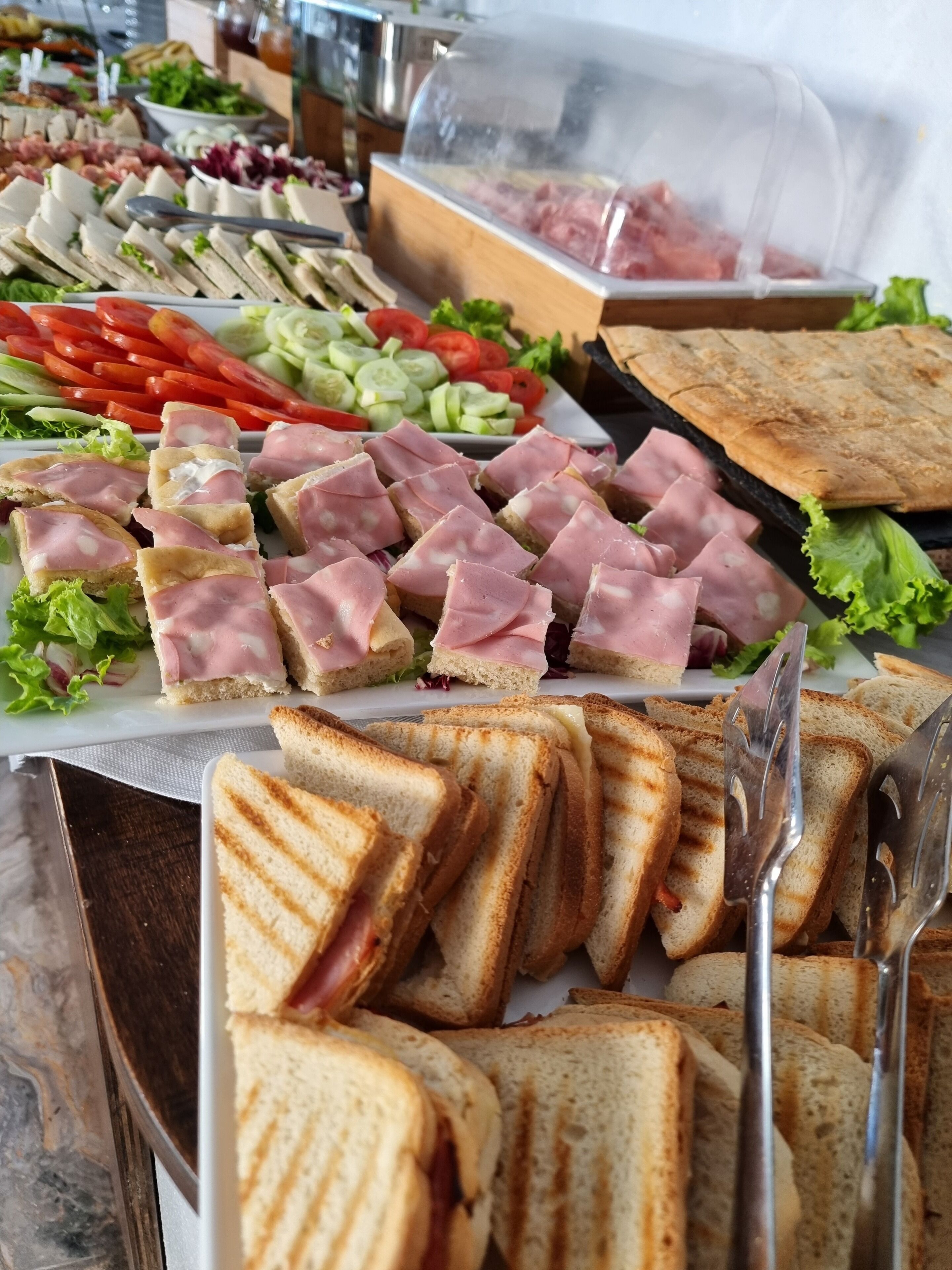 Un bufé con diversas opciones de comida, como sándwiches, ensaladas y carnes.