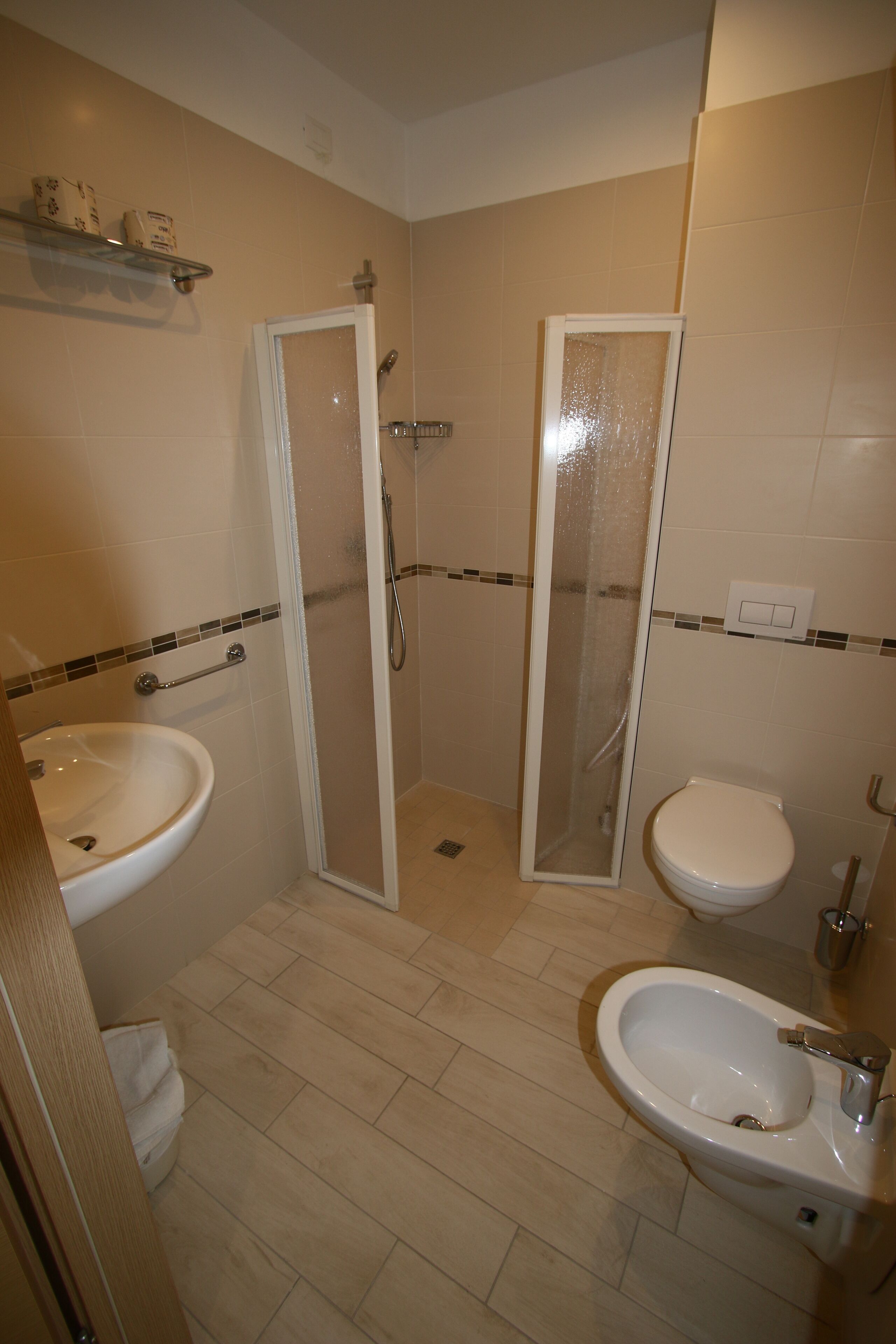 A bathroom with a shower, two sinks, and a toilet.