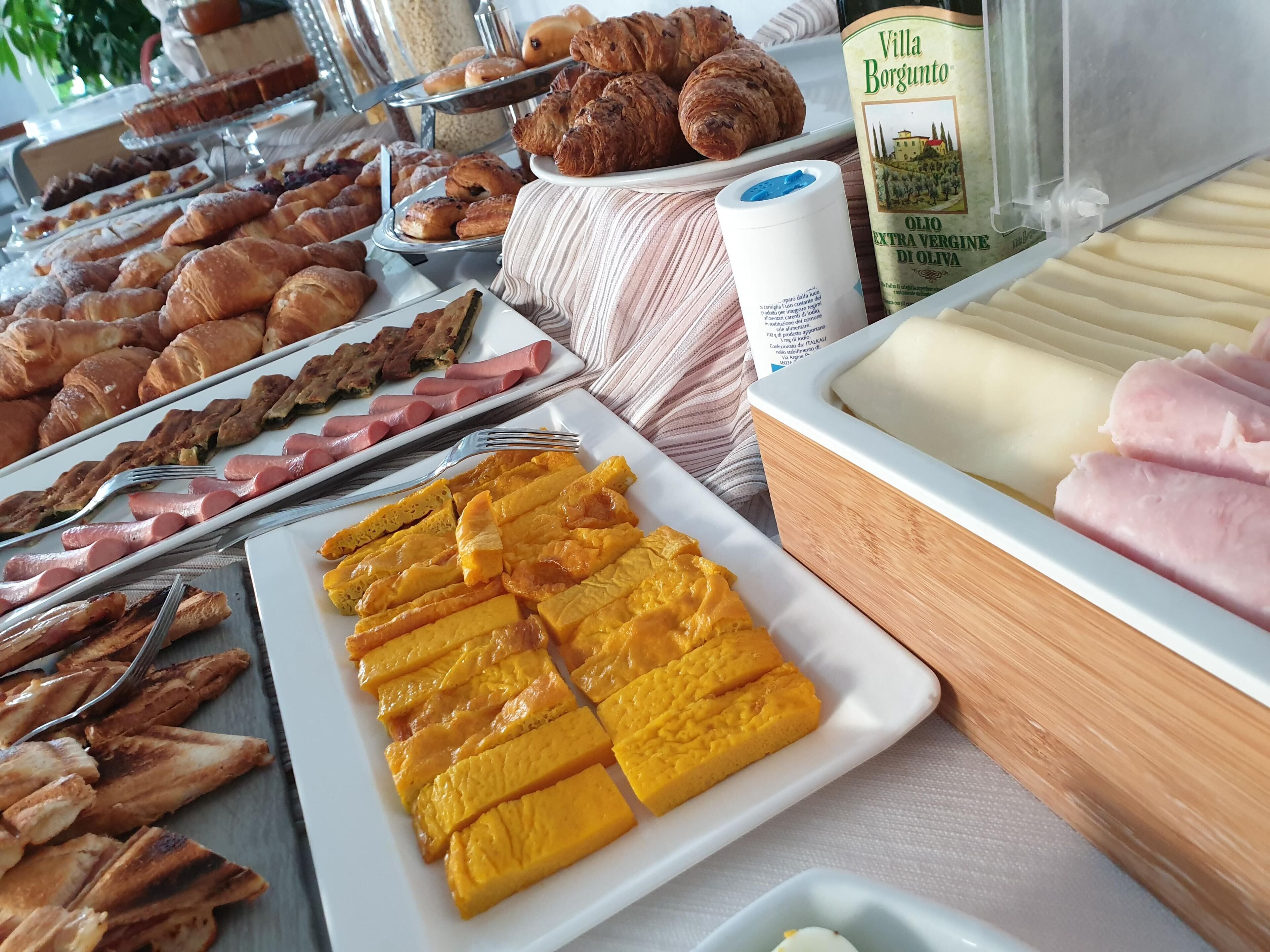 A buffet with various food items including pastries, meats, and cheese.