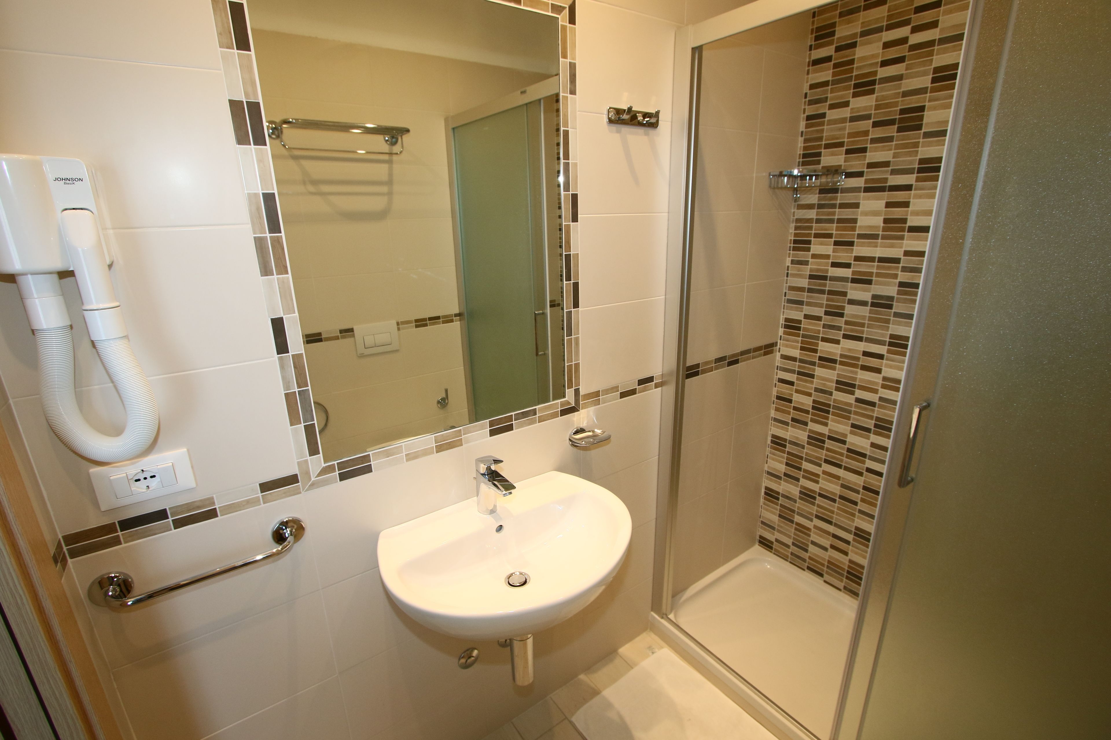 A bathroom with a white sink, a mirror, and a shower area.