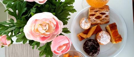 Ein Frühstückstisch mit Blumen, Orangensaft, Gebäck und Obstwürfeln.