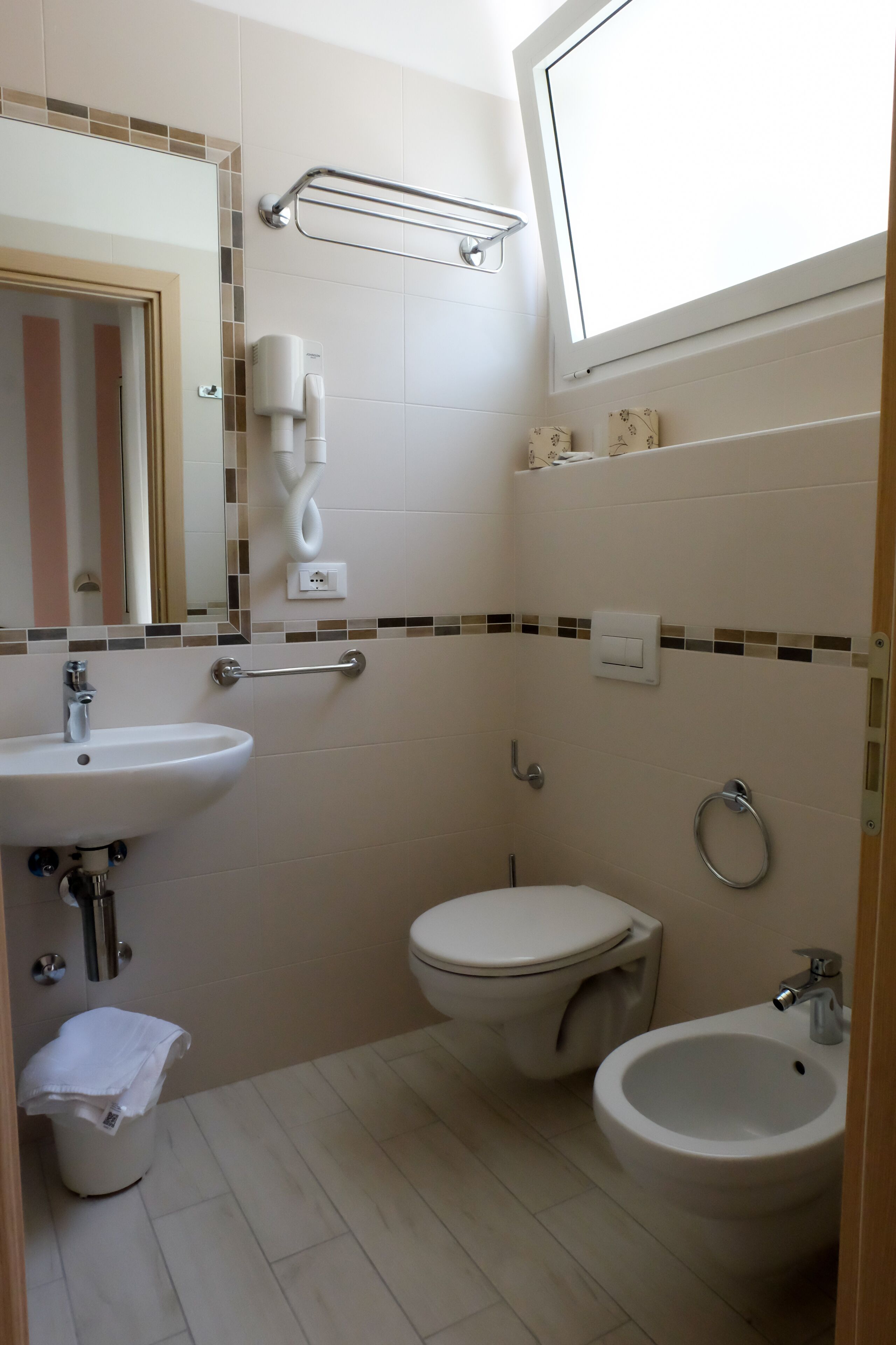 Un baño con lavamanos, inodoro, bidé y espejo.