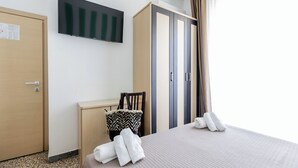 A hotel room with a bed, a desk, a wardrobe, and a flat-screen TV mounted on the wall. - Beach Hotel Clerice (Rimini)