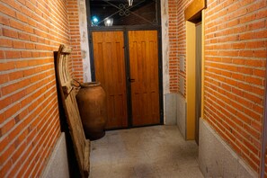 A narrow hallway with brick walls, a wooden door, and a large pot.