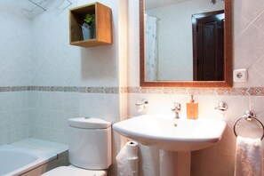 A bathroom with a toilet, sink, and mirror.