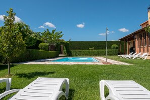 A swimming pool with lounge chairs, surrounded by well-maintained grass and hedges. - Casa Rural Tio Pancho (Solosancho)
