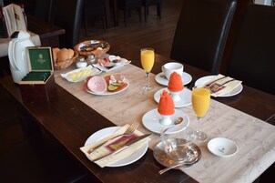 Disposição para o café da manhã com diversos alimentos, incluindo doces, frutas e um copo de suco de laranja.