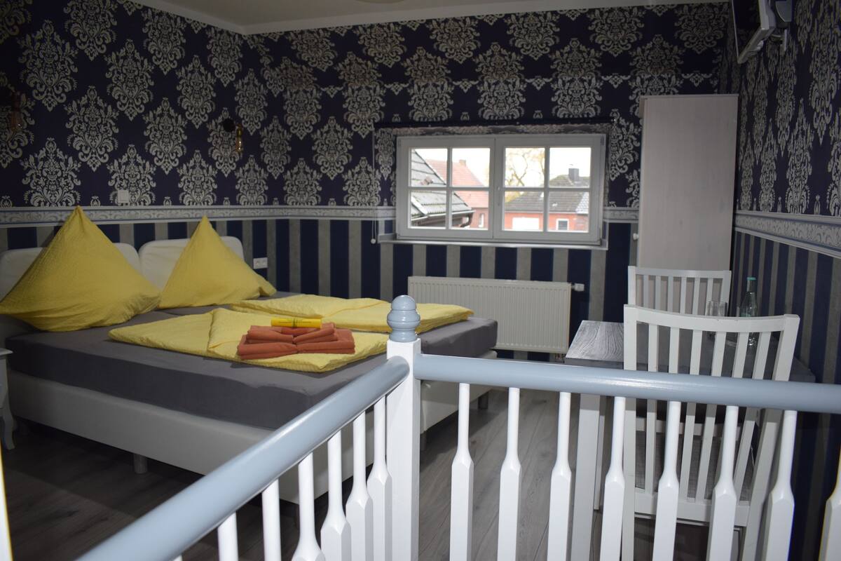 Una habitación con cama, cuna y ventana con vistas a edificios.