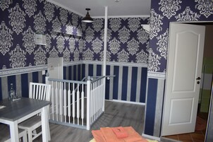 Um quarto com um corrimão branco, uma mesa com cadeiras e uma porta.