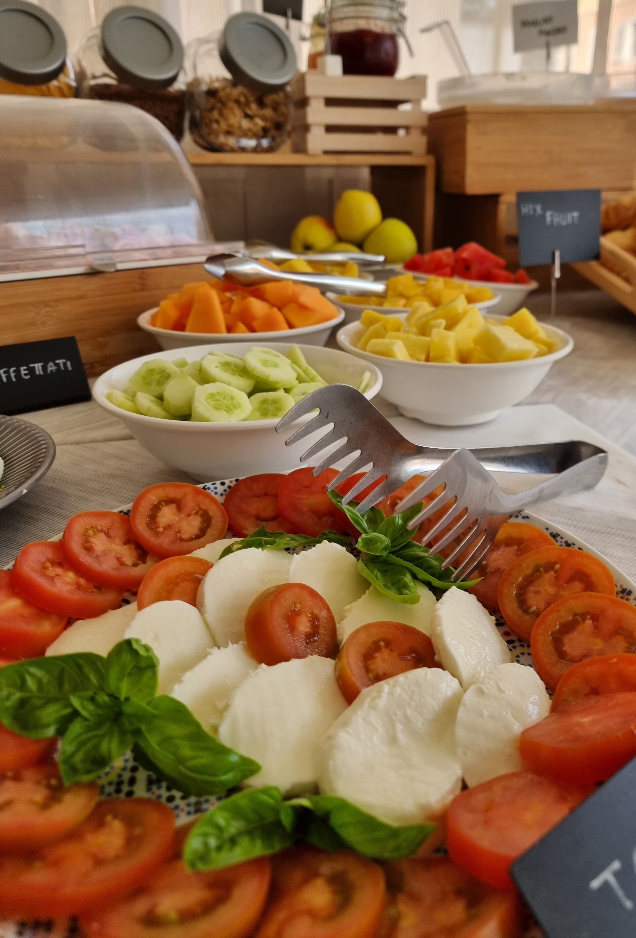 Un tavolo del buffet con diversi cibi, tra cui pomodori, mozzarella e un'insalata.