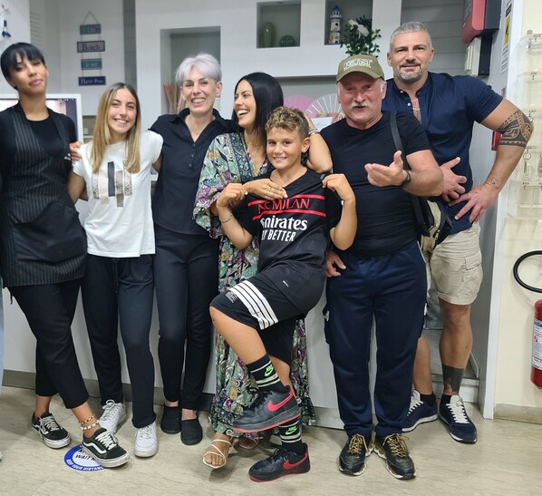 Um grupo de pessoas posando em um ambiente interno, com um extintor de incêndio e uma placa na parede à vista.