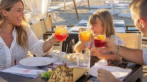 A beachside dining area with a table set for four, featuring a variety of dishes and drinks. - Hotel Kim (Rimini)