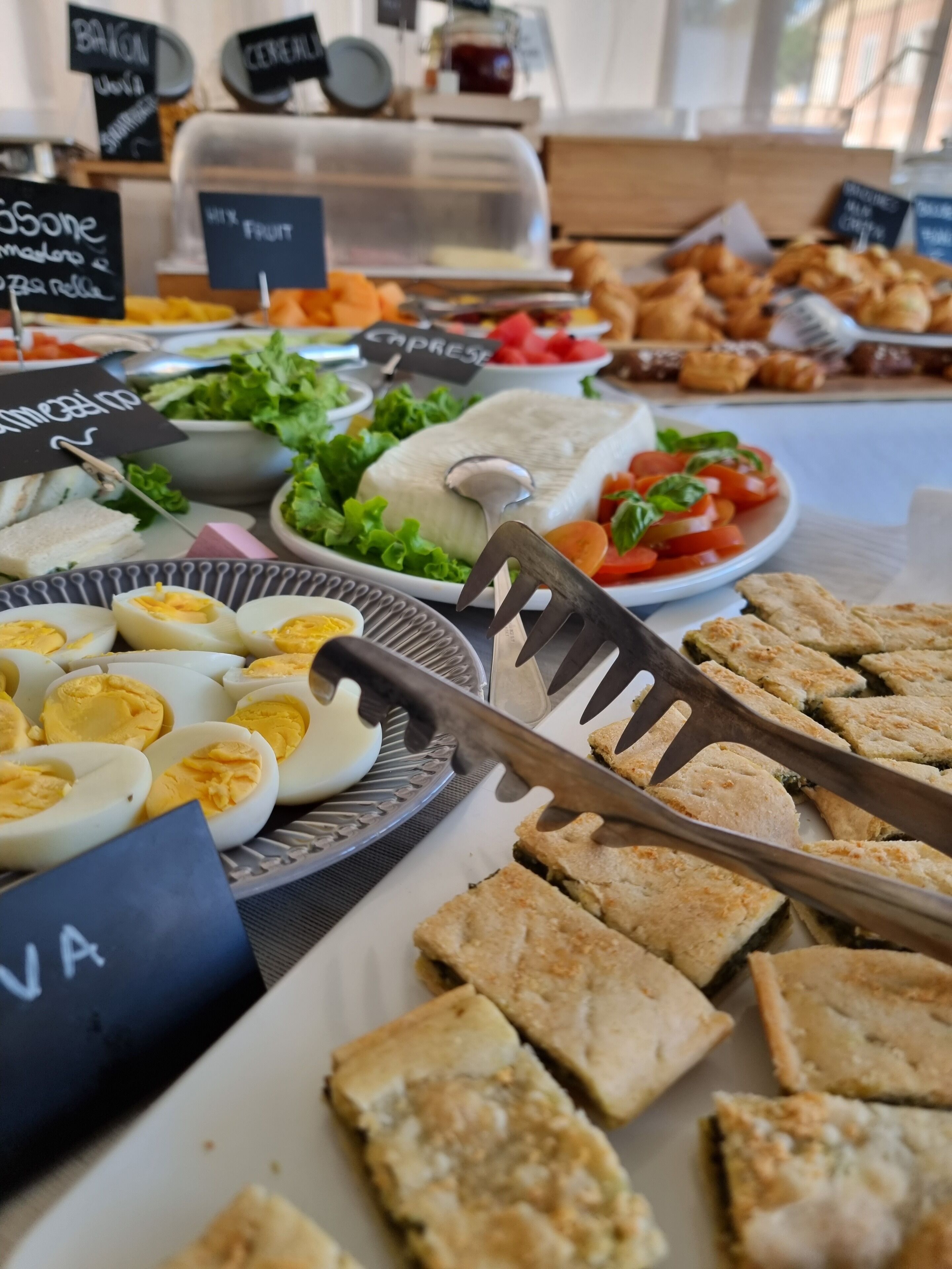 Un buffet proposant une variété de plats, notamment des œufs, des salades et des sandwichs.