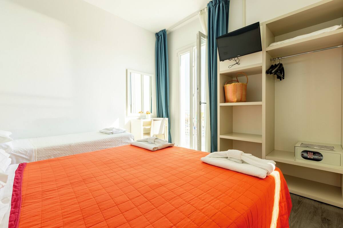 A hotel room with a bed, a desk, a wardrobe, and a bathroom.