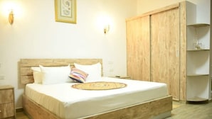 A bedroom with a large bed, wooden headboard, and a wardrobe. - Easy Stay Residence (Trou aux Biches)