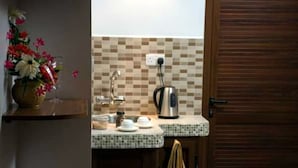 A kitchen with a tiled backsplash, a kettle, and a vase of flowers. - Easy Stay Residence (Trou aux Biches)