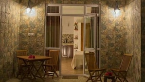 A dining area with a table and chairs, a stone wall, and a view into a kitchen. - Easy Stay Residence (Trou aux Biches)