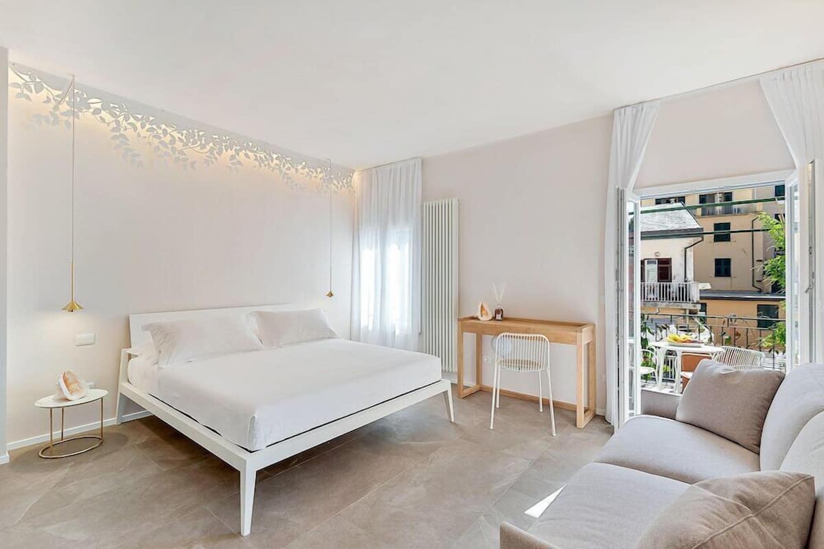 A modern bedroom with a bed, a desk, and a view of the outside.