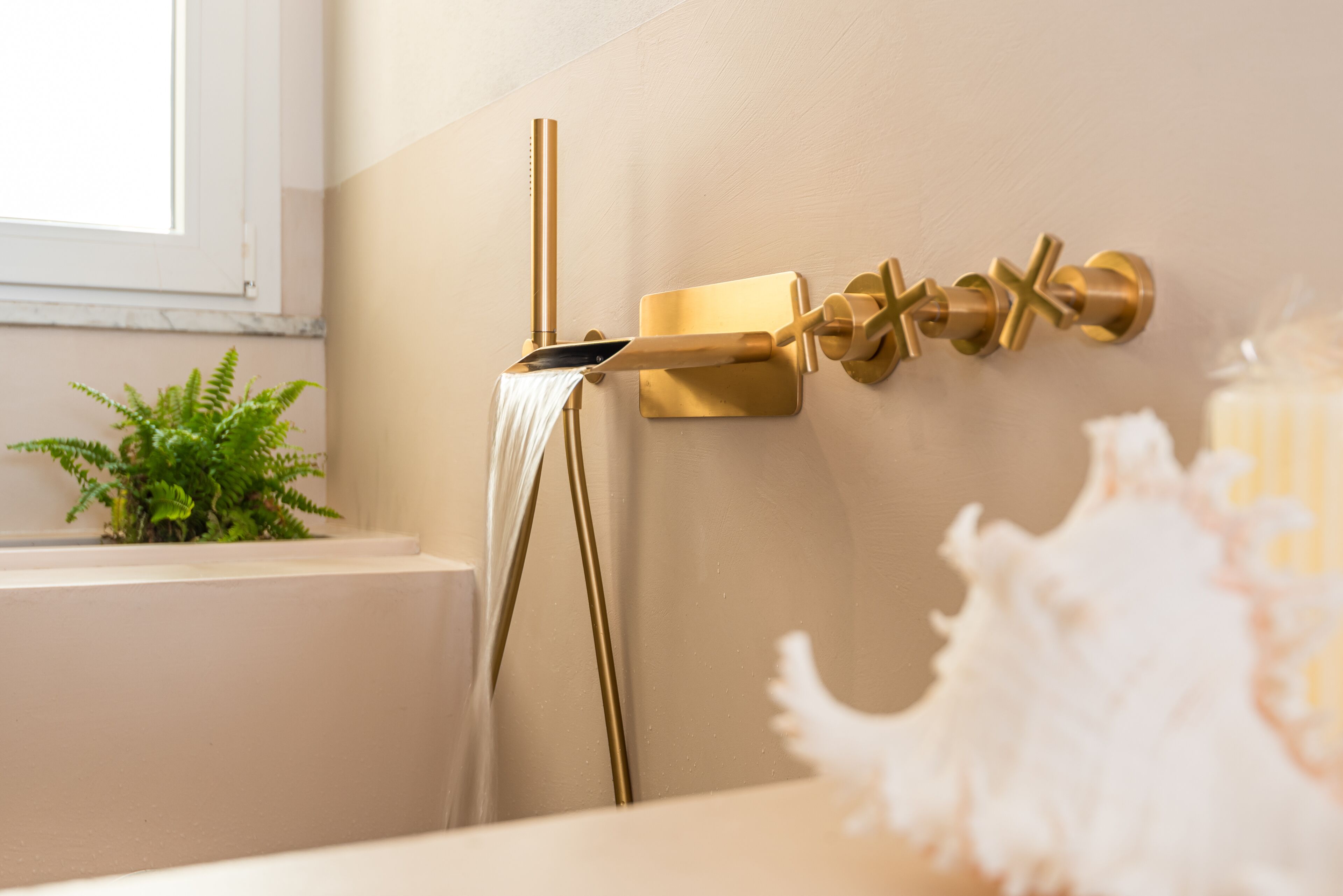 A bathroom with a gold faucet and a white towel hanging from it.
