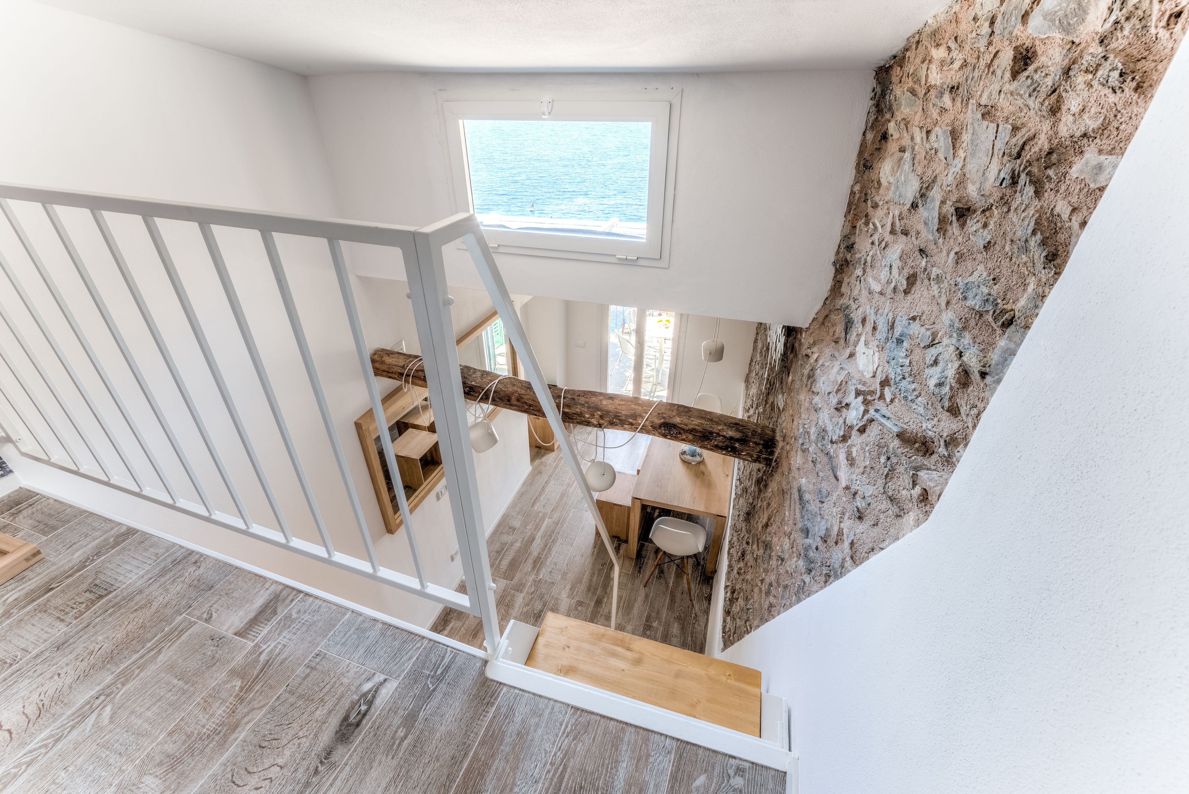 Una escalera conduce a un comedor con vista al mar a través de un ventanal.