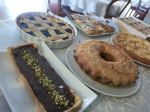 A variety of desserts on a table, including a chocolate-covered pastry with nuts, a pie, and a donut. - Agriturismo Corte Trincerone (Mantua)