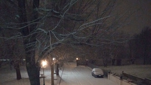 A snow-covered street at night with street lamps and a parked car. - Agriturismo Corte Trincerone (Mantua)
