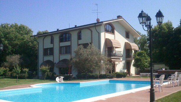 A large building with a swimming pool, surrounded by greenery and outdoor seating. - Agriturismo Corte Trincerone (Mantua)