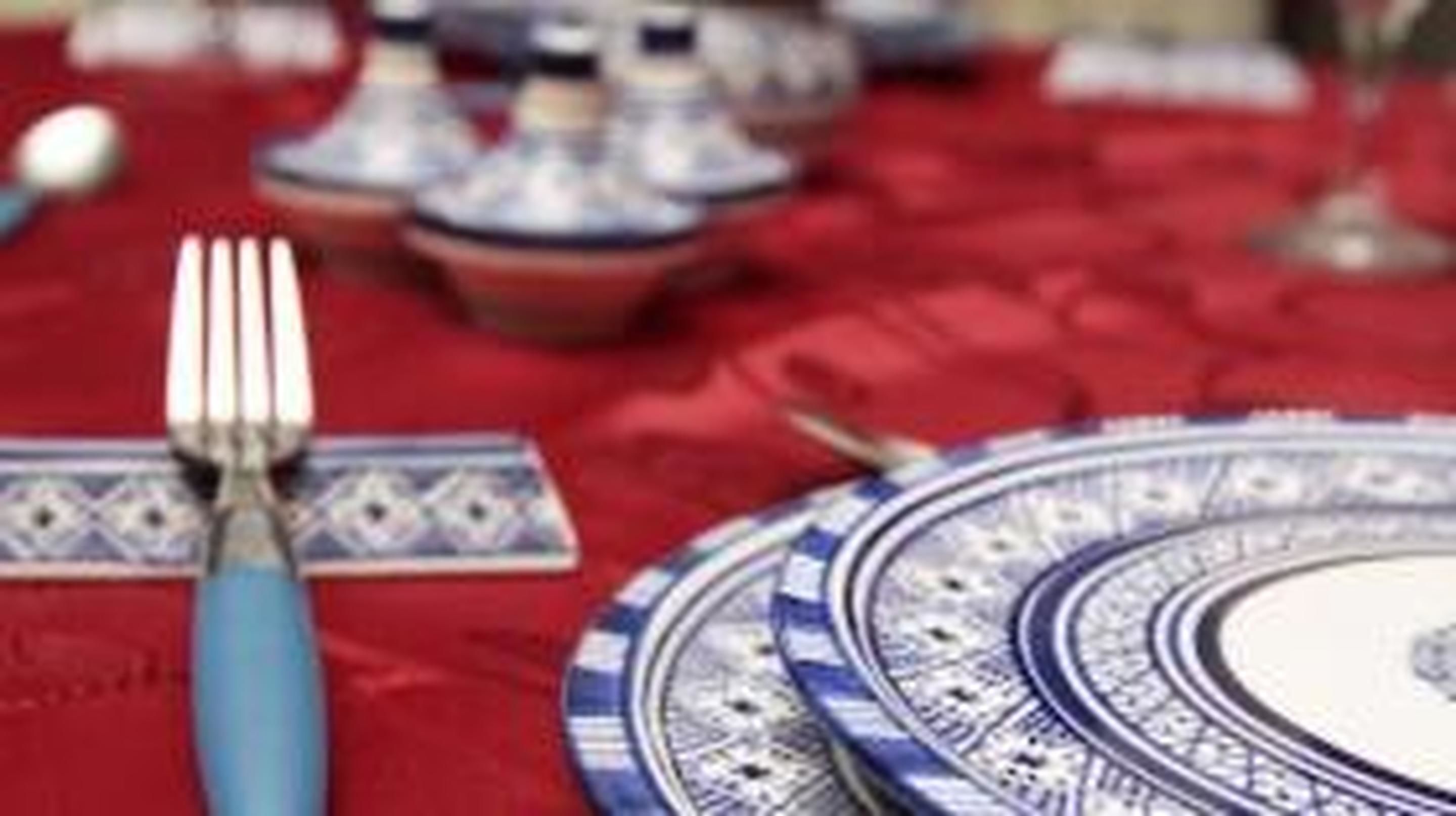 Uma mesa posta com um prato azul e branco estampado, um garfo e uma colher.
