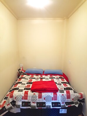 A small, neatly made bed with a patterned bedspread and two pillows. - Suite Capivari Room (Campos do Jordão)