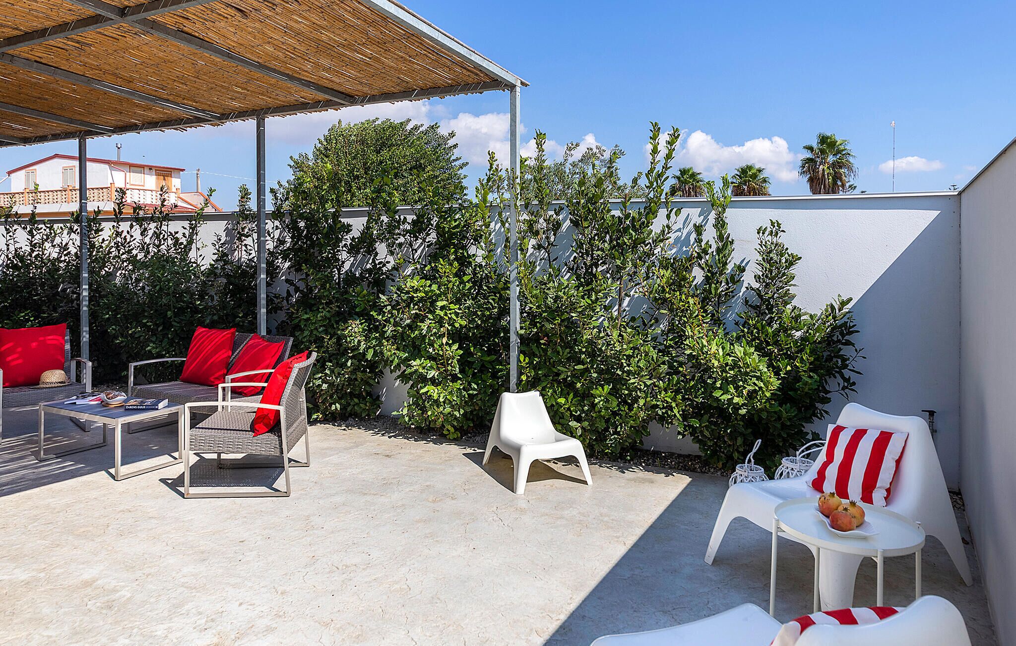An outdoor patio with wicker furniture, a table, and a covered area.