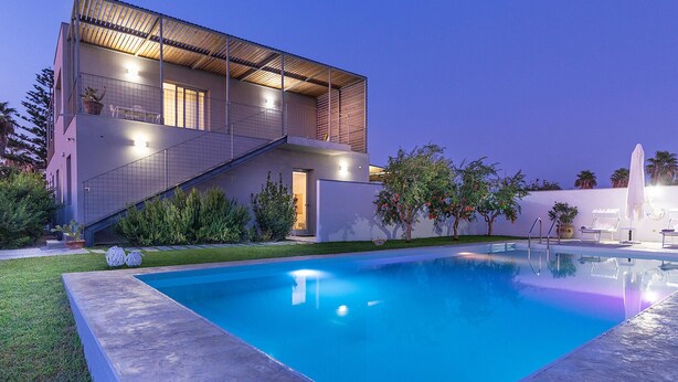 A modern house with a swimming pool, a covered outdoor area, and a staircase leading to the upper floor.