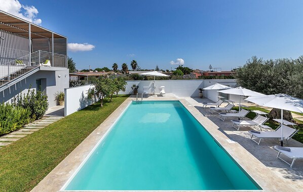 Relax by the pool surrounded by lush greenery and comfortable lounge seating.
