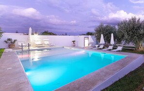 Relax by the serene pool surrounded by lounge chairs and lush greenery.