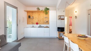 A modern kitchen with white cabinets, a wooden countertop, and a dining area with a wooden table and chairs.