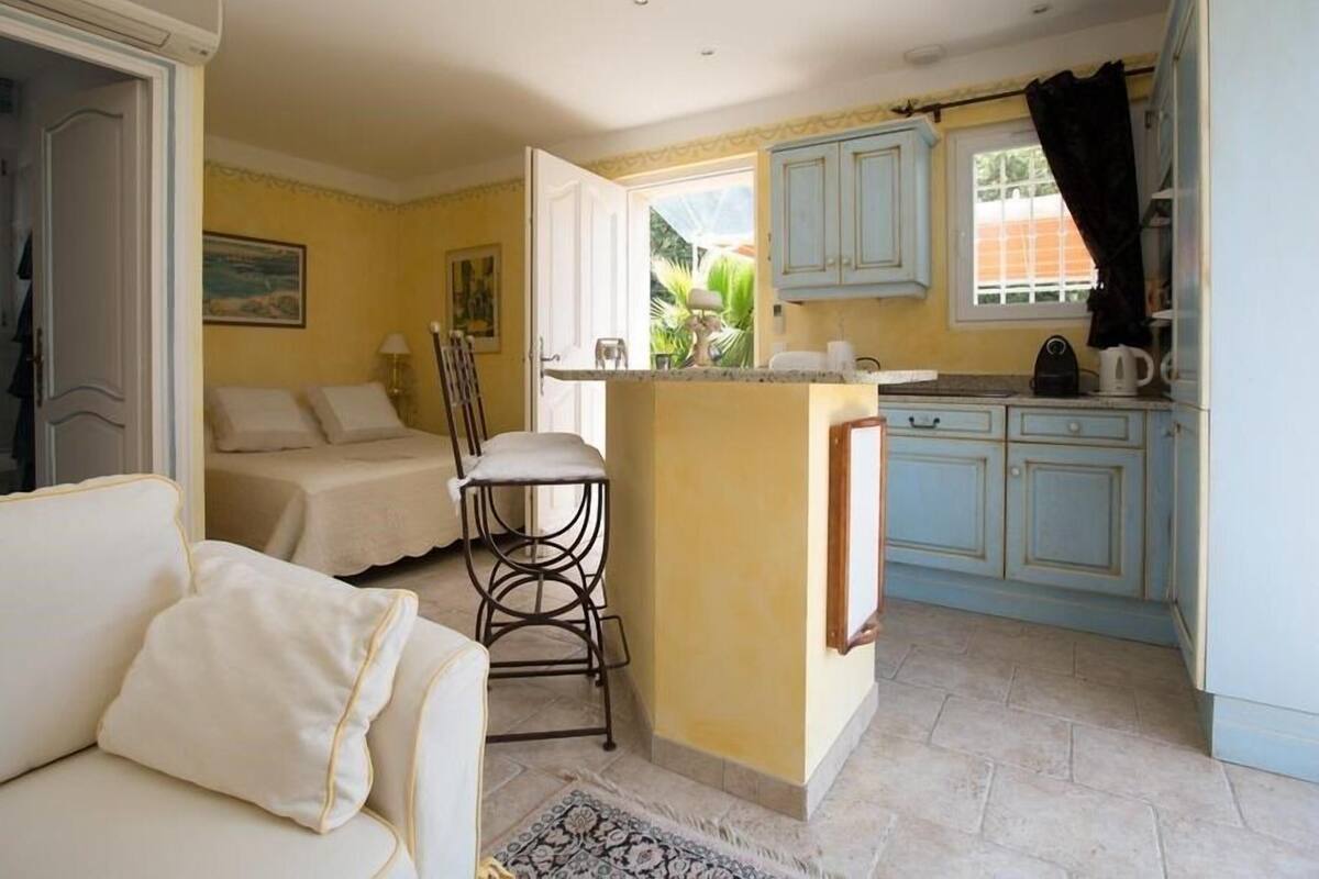 Una habitación de hotel compacta con cama, una pequeña mesa de comedor, una silla y una kitchenette.
