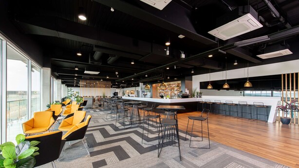 A modern bar area with high stools, a bar counter, and a seating area with chairs and tables. - Rydges Pit Lane Hotel (Tailem Bend)