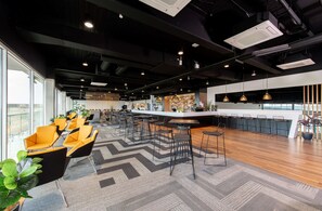 A modern bar area with high stools, a bar counter, and a seating area with chairs and tables.