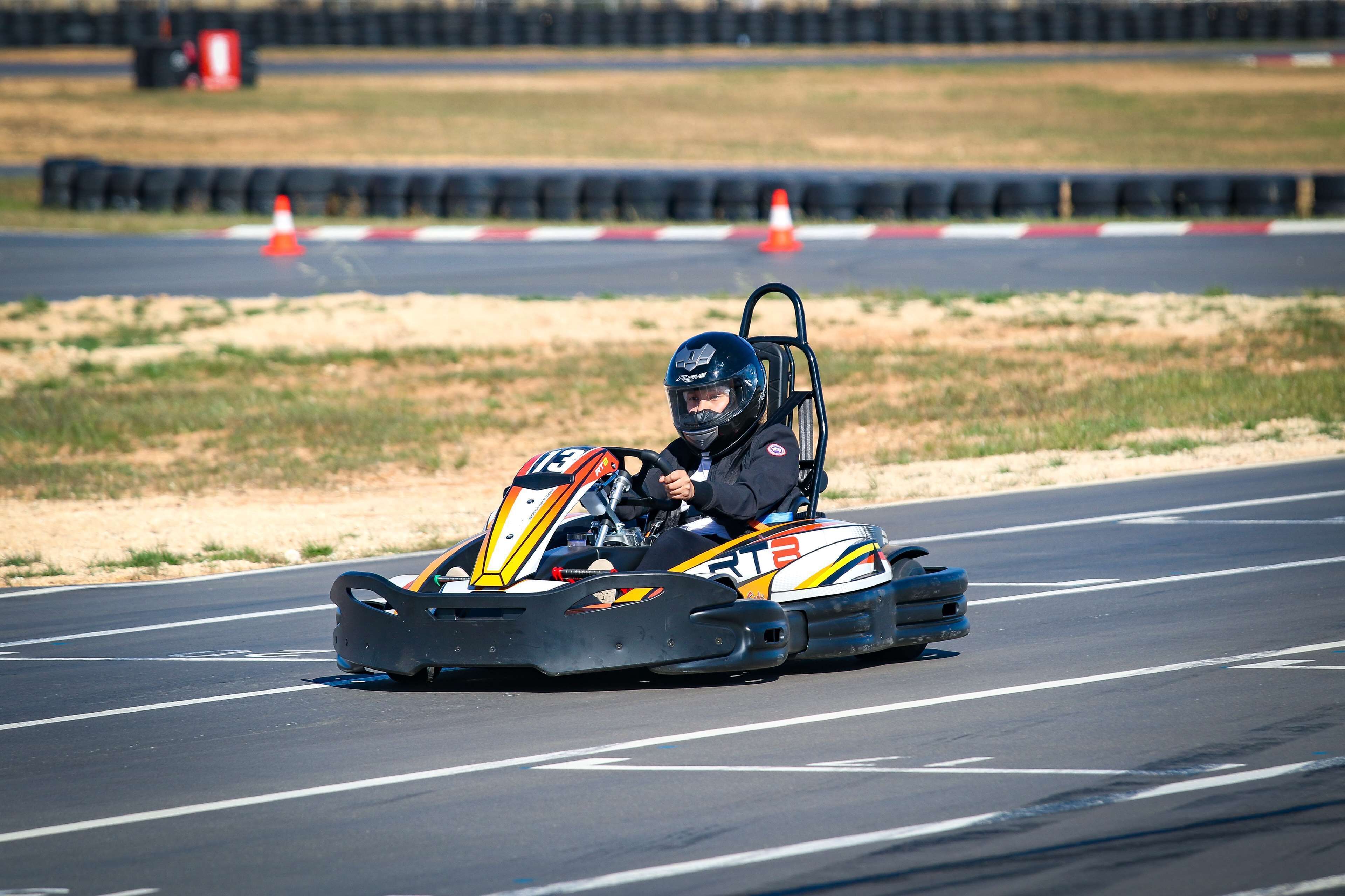 Een raceauto op een circuit, met een bestuurder in helm en racetermijn.