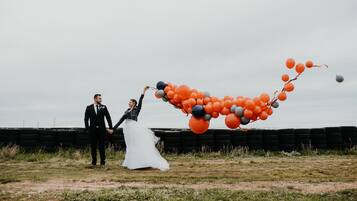 Escena de boda con una pareja sosteniendo una guirnalda de globos.
