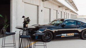 A black sports car parked in front of a building with closed shuttered doors.