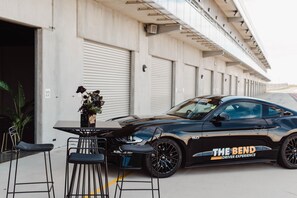 A black sports car parked in front of a building with closed shuttered doors.