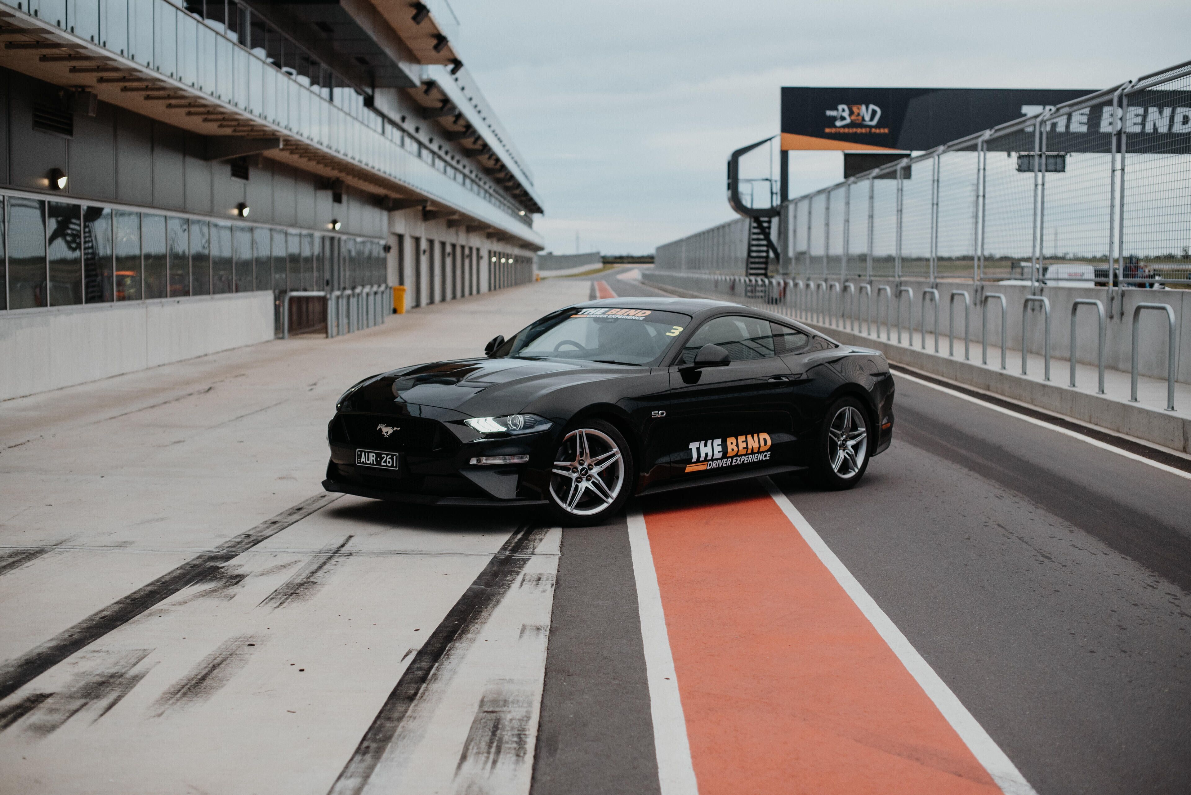 A black sports car parked on a racetrack with a red and white lane marking.