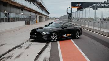 A black sports car parked on a racetrack with a red and white lane marking.