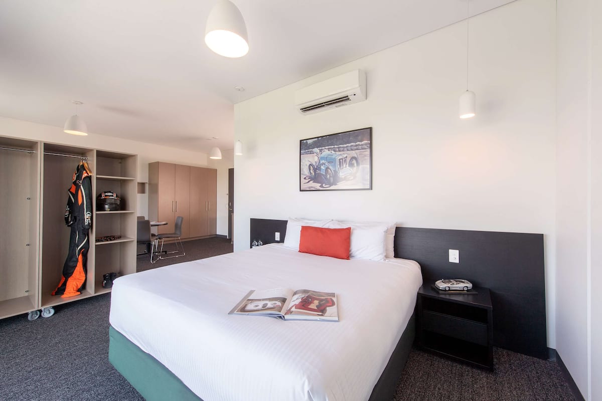 A hotel room with a large bed, a wardrobe, a desk, and a chair.