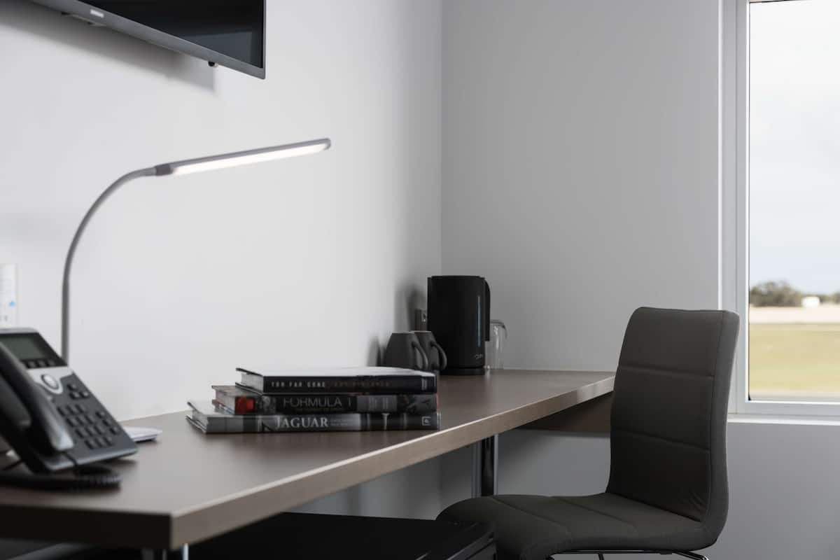 A modern office desk with a lamp, a phone, and books.