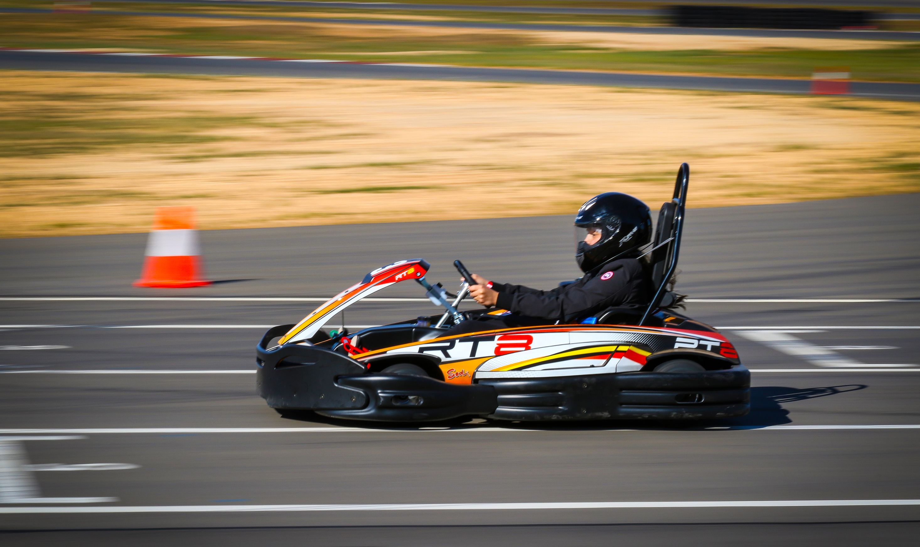 A go-kart on a track with a driver wearing a helmet.