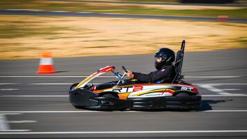 A go-kart on a track with a driver wearing a helmet.
