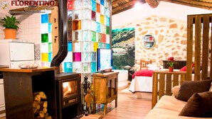A rustic interior with a wood-burning stove, a stone wall, and a cozy seating area. - Casa Rural El Cuco (Solosancho)
