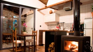 A cozy kitchen with a wood-burning stove, wooden furniture, and a tiled backsplash. - Casa Rural El Cuco (Solosancho)